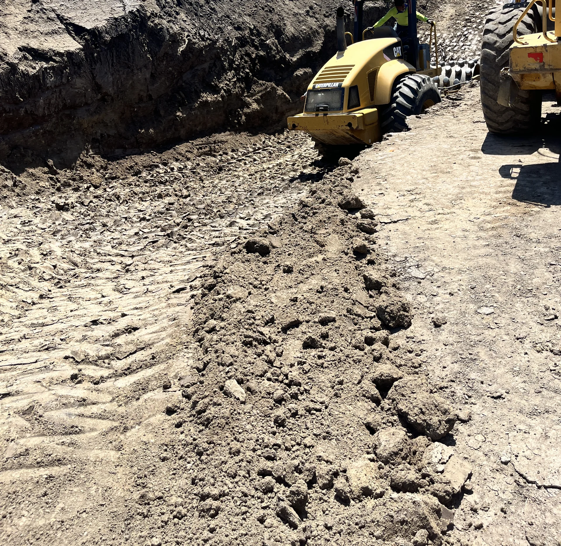 Deep excavation cut down to firm material on a hillside lot with a compactor working
