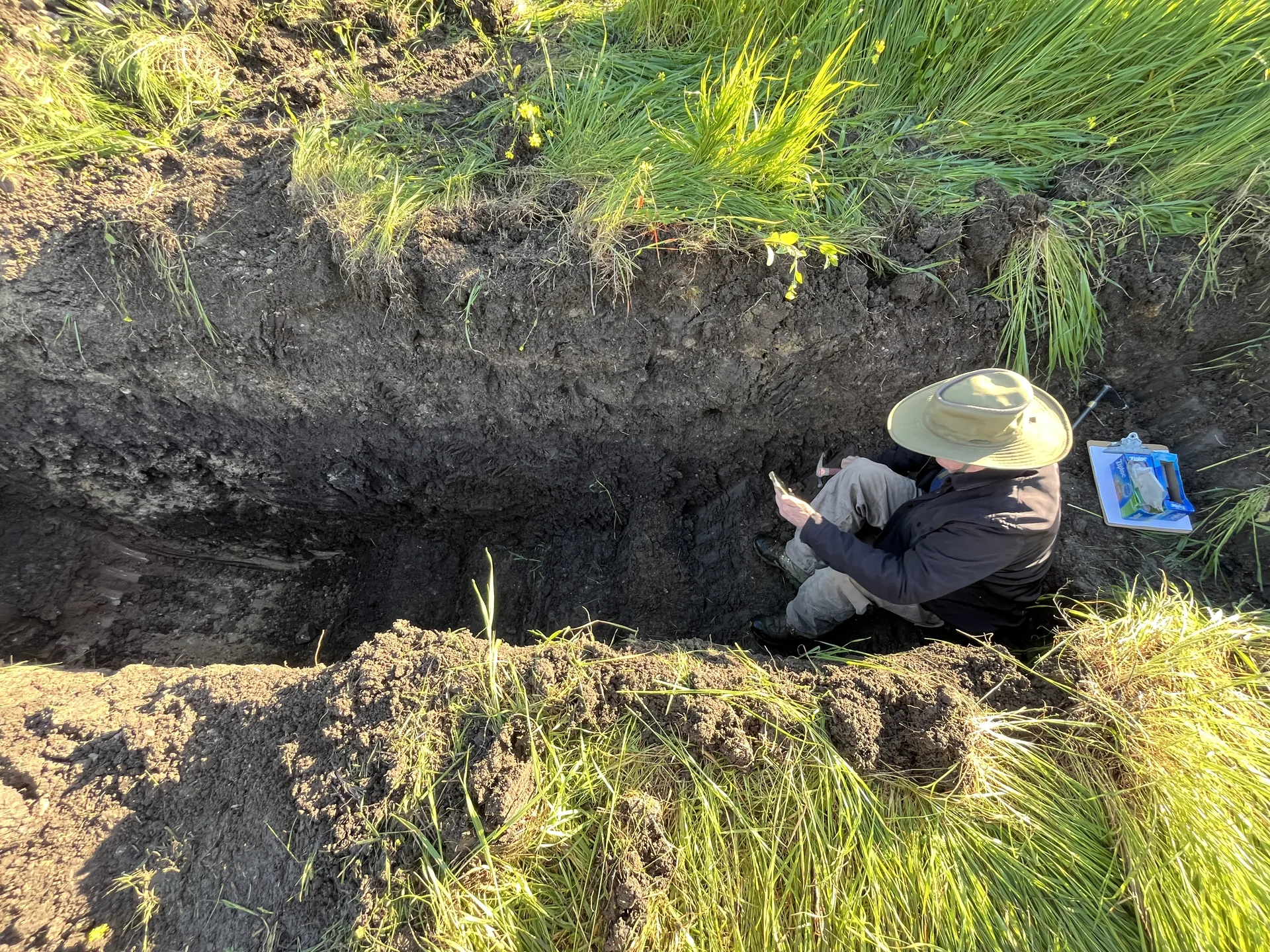Engineering geologist logging soil layers inside a test pit